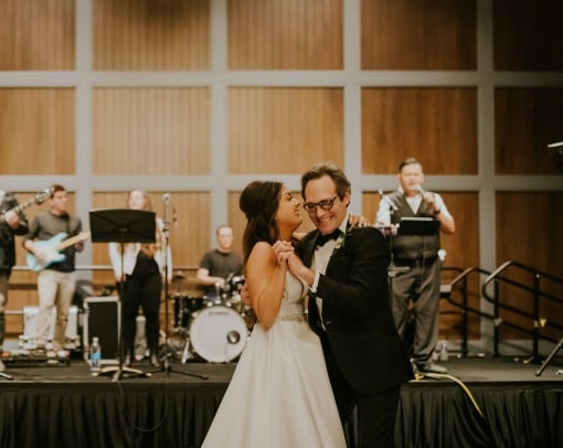 Bride dancing with her father in front of a live band