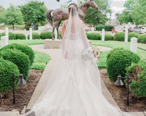 Woman in a wedding dress walking by lush greenery